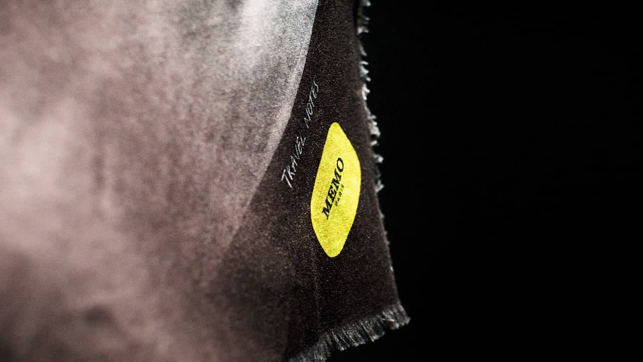Black textured fabric scarf with a frayed edge and a bright yellow oval memo label.