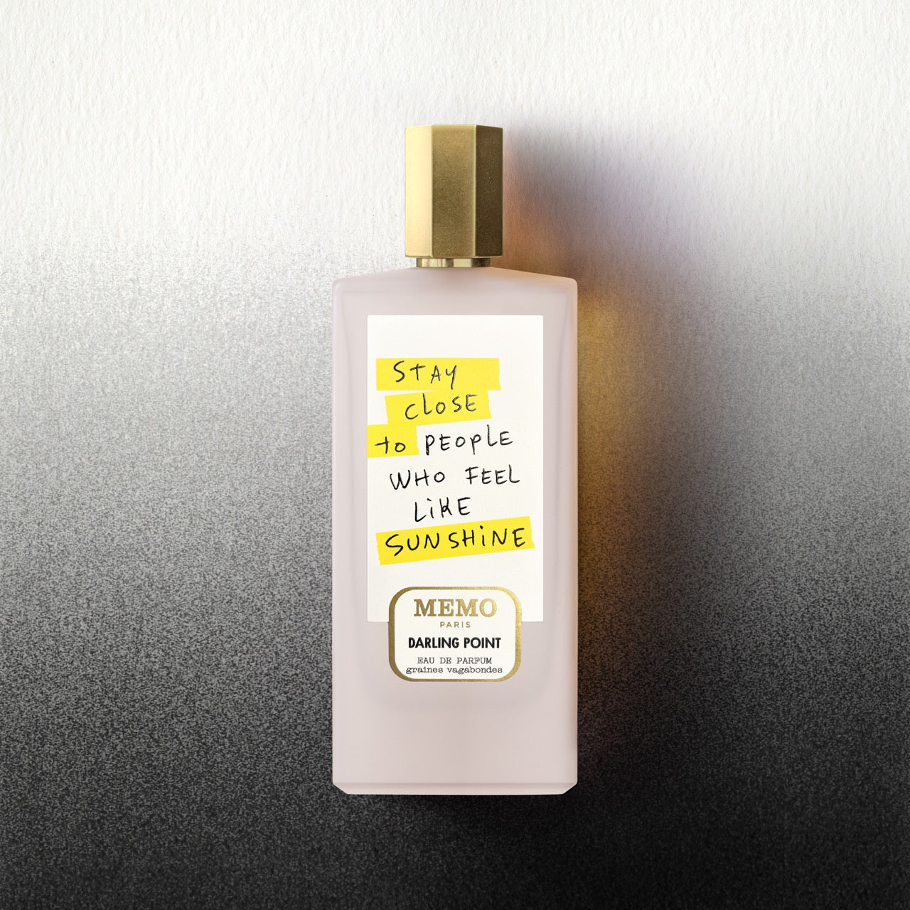 A pale pink rectangular perfume bottle with a gold cap and handwritten label by memo paris darling point x thomas lelu
