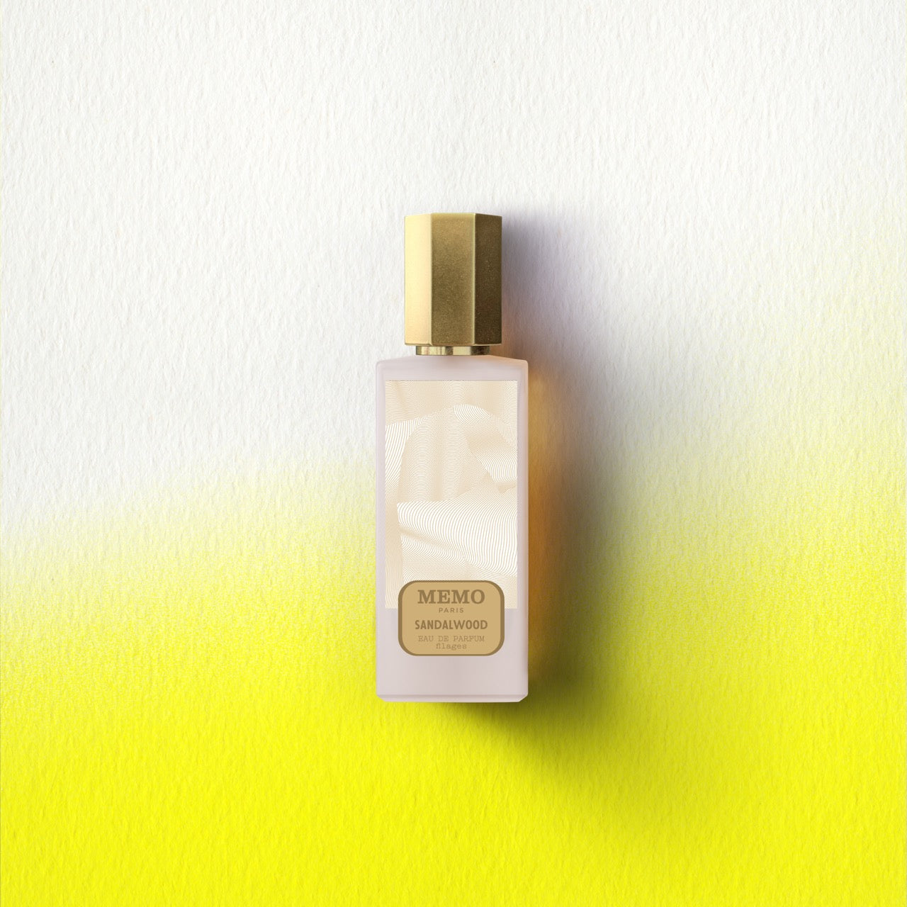 A sleek frosted glass memo paris essences filages sandalwood eau de parfum bottle with a polished gold cap