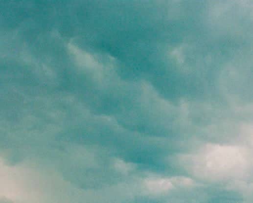 Soft, wispy clouds drift across a serene teal sky.