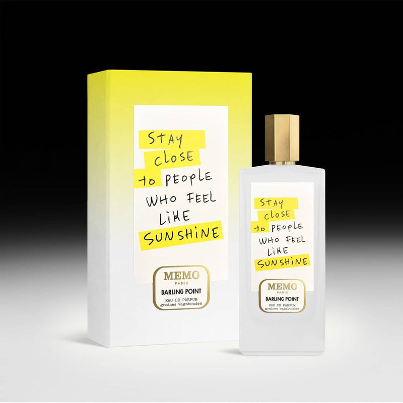 A white rectangular perfume bottle with a gold cap and handwritten-style yellow text on its label, featuring the ’memo paris’ brand.